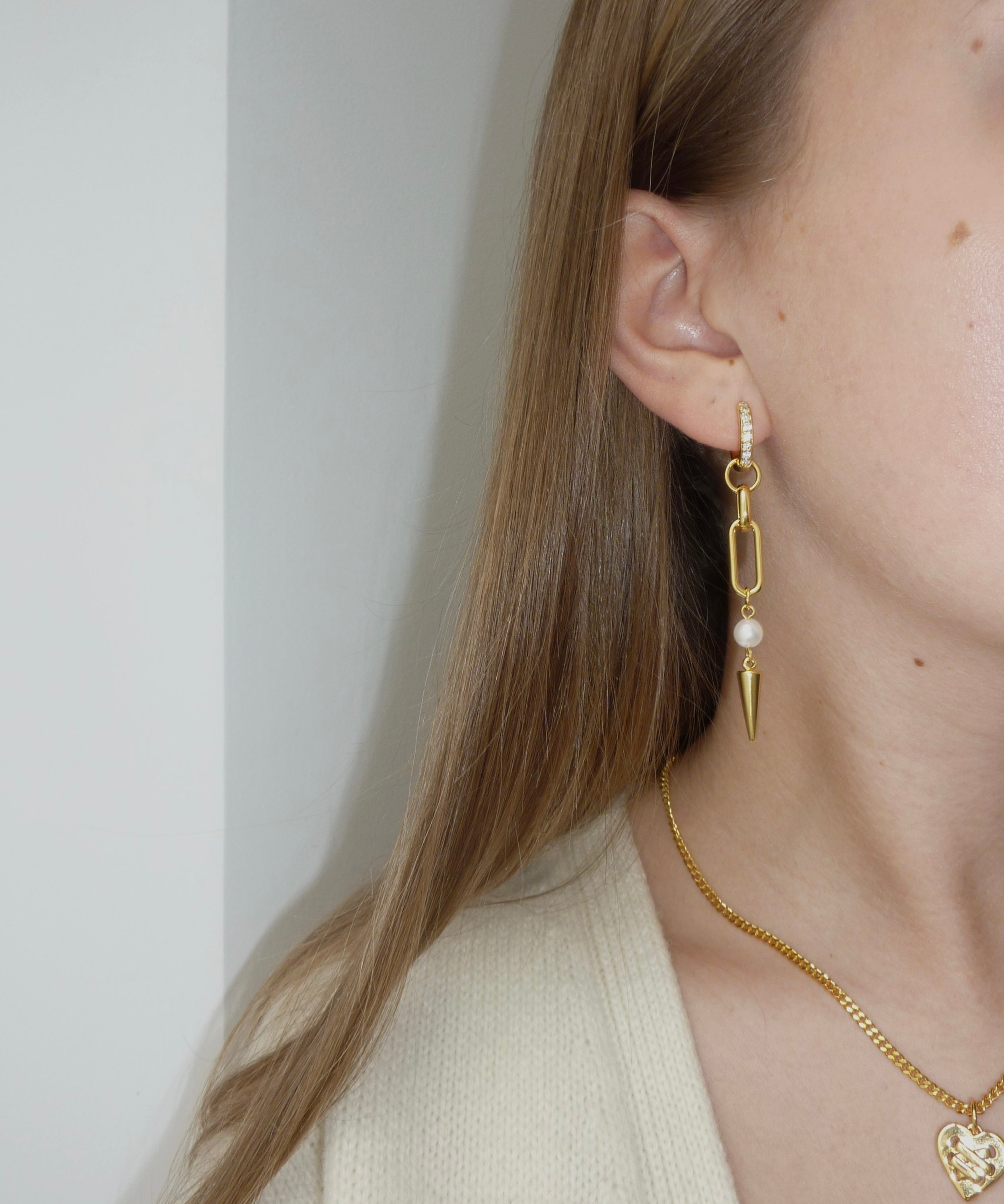 Adora Earrings in gold worn with heart necklace, close-up side view